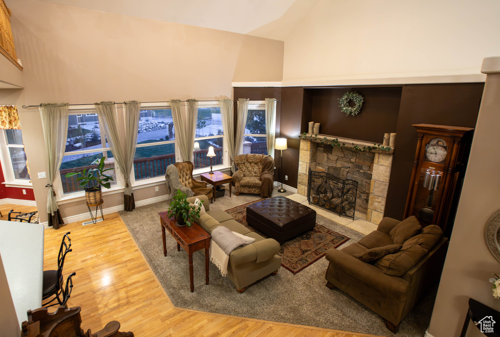 Living area with wood finished floors, a fireplace, and high vaulted ceiling