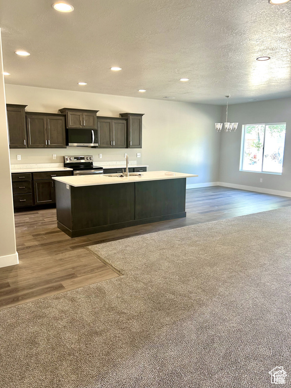 Kitchen with appliances with stainless steel finishes, a sink, a chandelier, light countertops, and recessed lighting