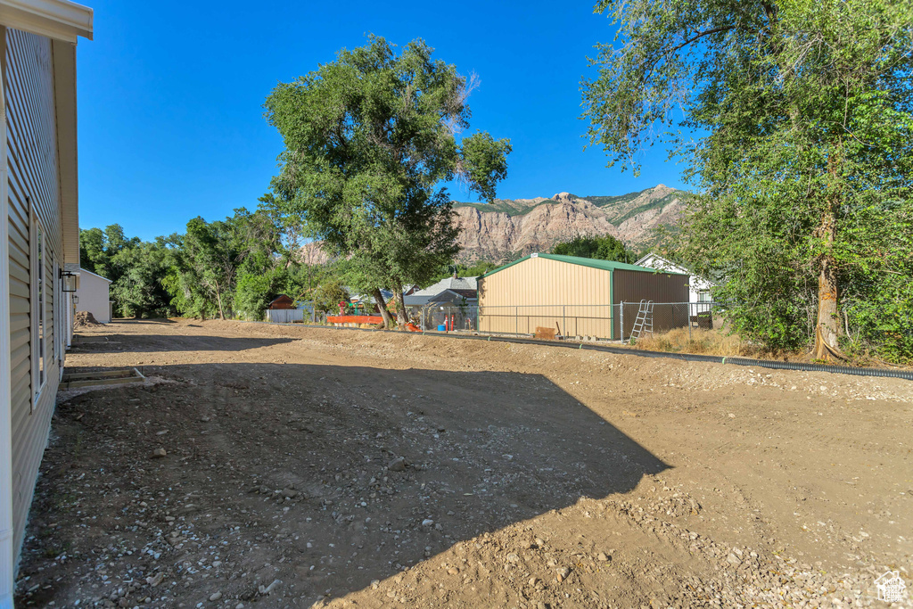 View of yard with a pole building, a mountain view, and an outdoor structure