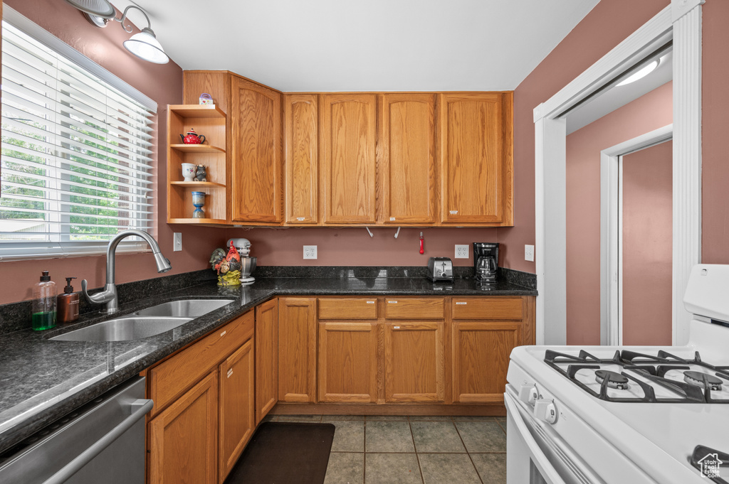 Kitchen with gas range gas stove, stainless steel dishwasher, a sink, light tile patterned floors, and open shelves