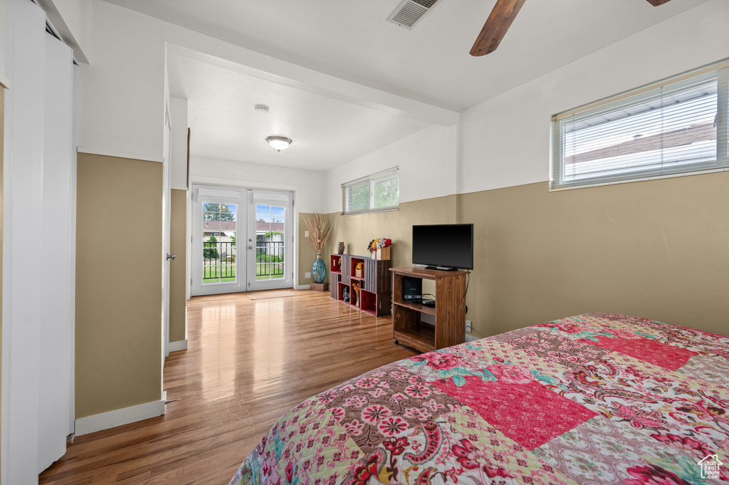 Bedroom featuring access to exterior, wood finished floors, french doors, and ceiling fan