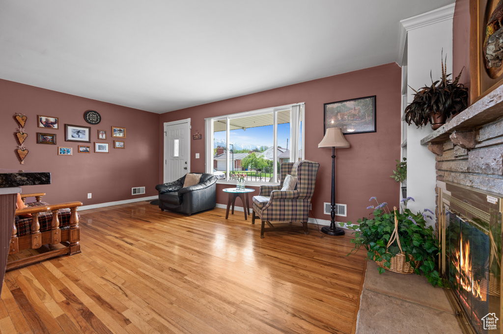 Living room featuring light wood-style floors, a stone fireplace, and baseboards