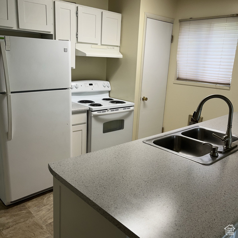 Kitchen with white appliances, under cabinet range hood, and white cabinets