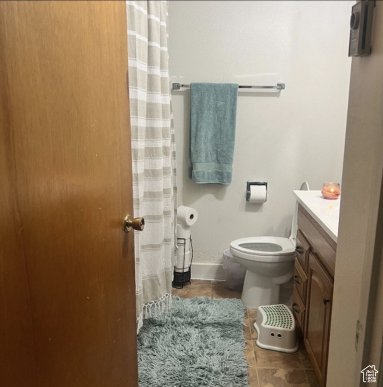 Full bath featuring tile patterned floors, toilet, vanity, baseboards, and a shower with shower curtain