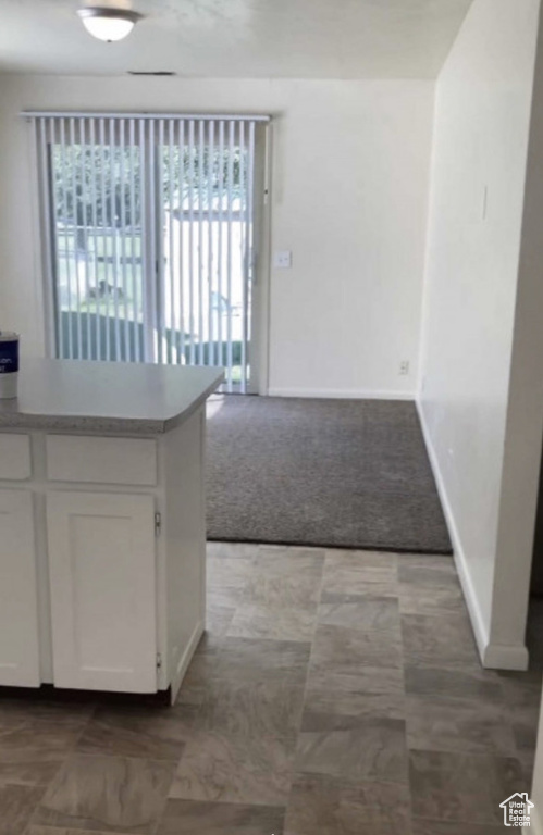 Kitchen with plenty of natural light, white cabinets, carpet floors, and light countertops