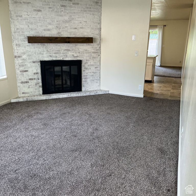 Unfurnished living room with carpet and a fireplace