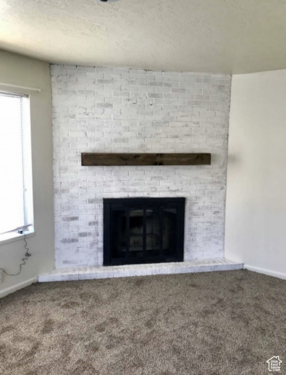 Detailed view of carpet flooring, a fireplace, and baseboards