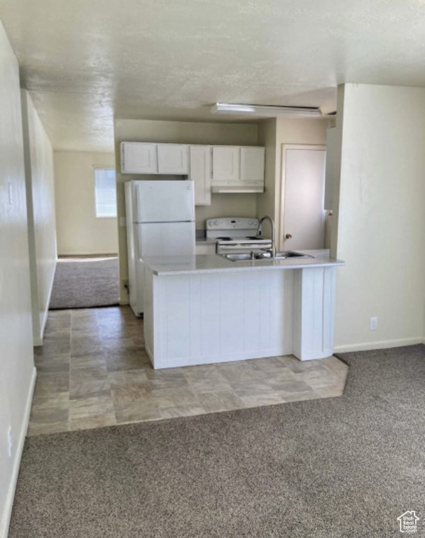 Kitchen with white appliances, light carpet, baseboards, white cabinetry, and light countertops