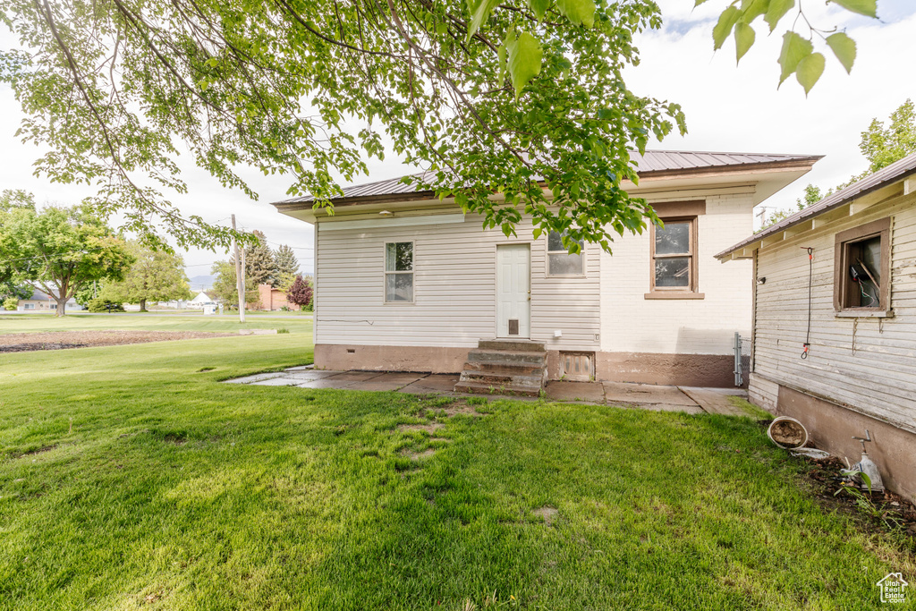 Back of house featuring a lawn, metal roof, and entry steps