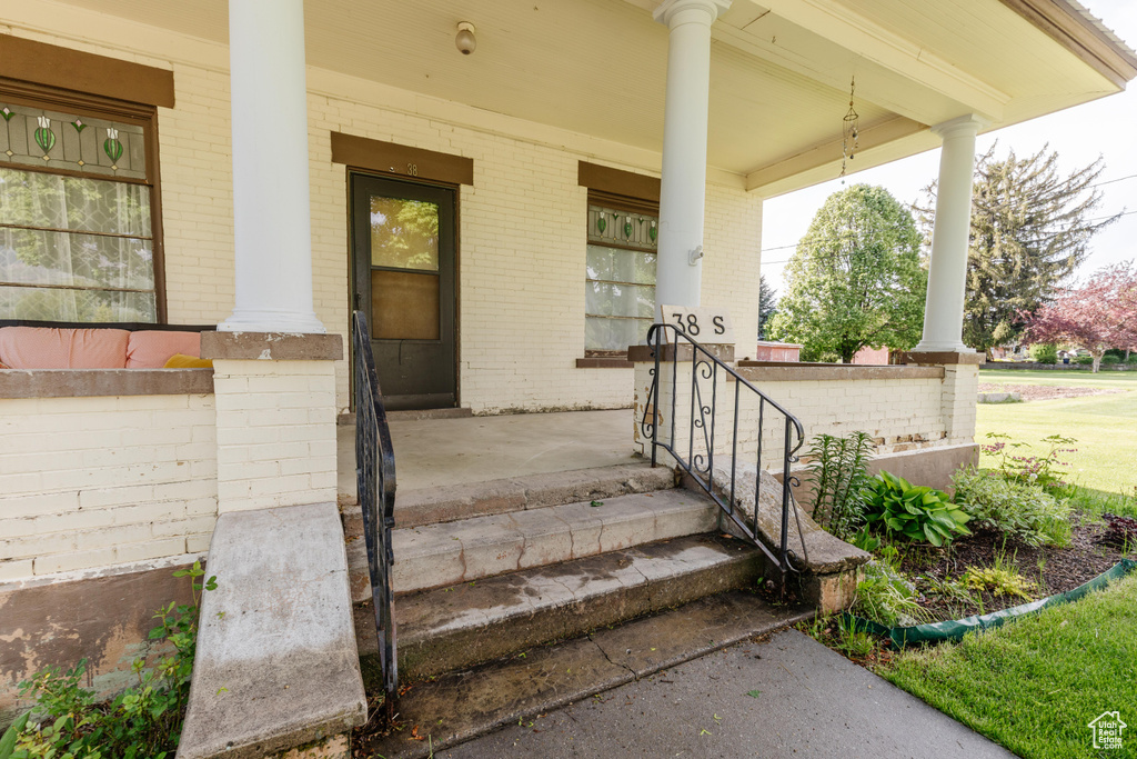 Doorway to property with covered porch and brick siding
