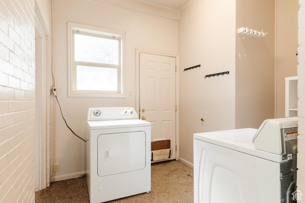 Laundry room featuring washer and dryer, light carpet, and baseboards