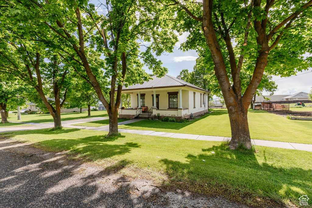 View of front of house featuring a front lawn, a porch, and metal roof