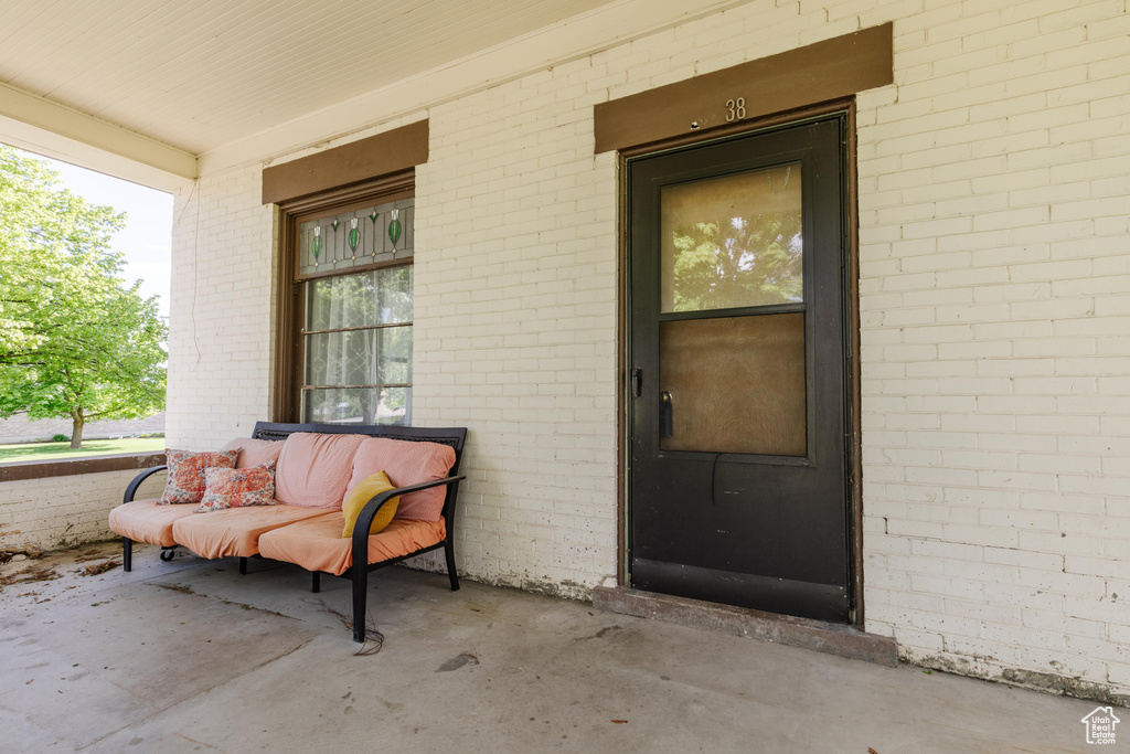 Entrance to property with a porch and brick siding