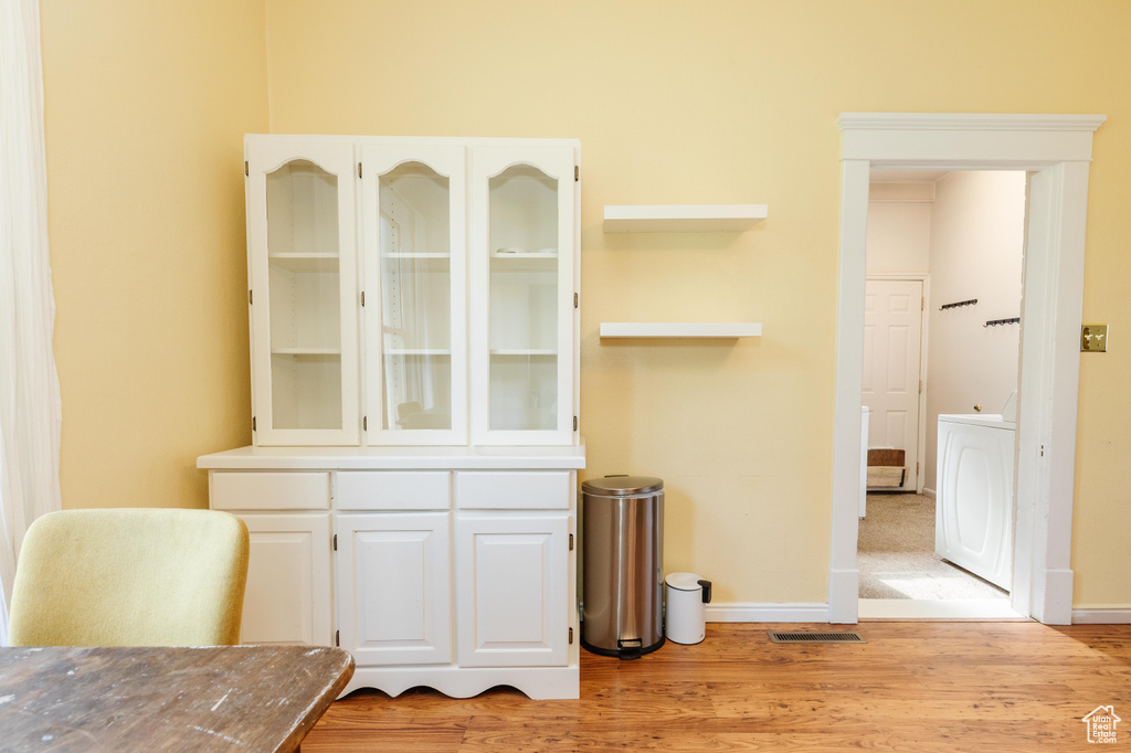 Unfurnished dining area with washer / dryer, light wood-style flooring, and baseboards