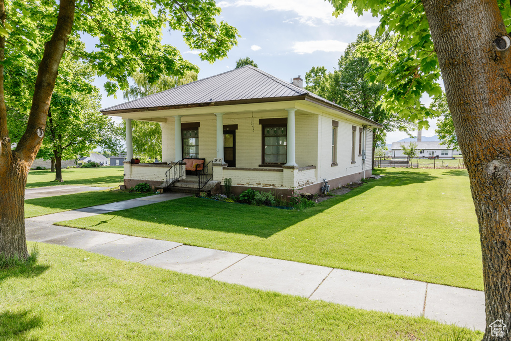 View of front facade featuring brick siding, a chimney, and a porch
