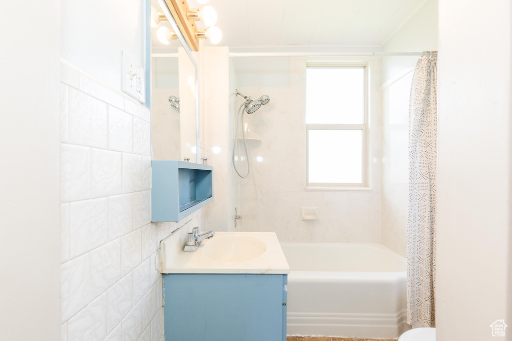 Full bathroom with shower / bath combo with shower curtain, vanity, and tile walls