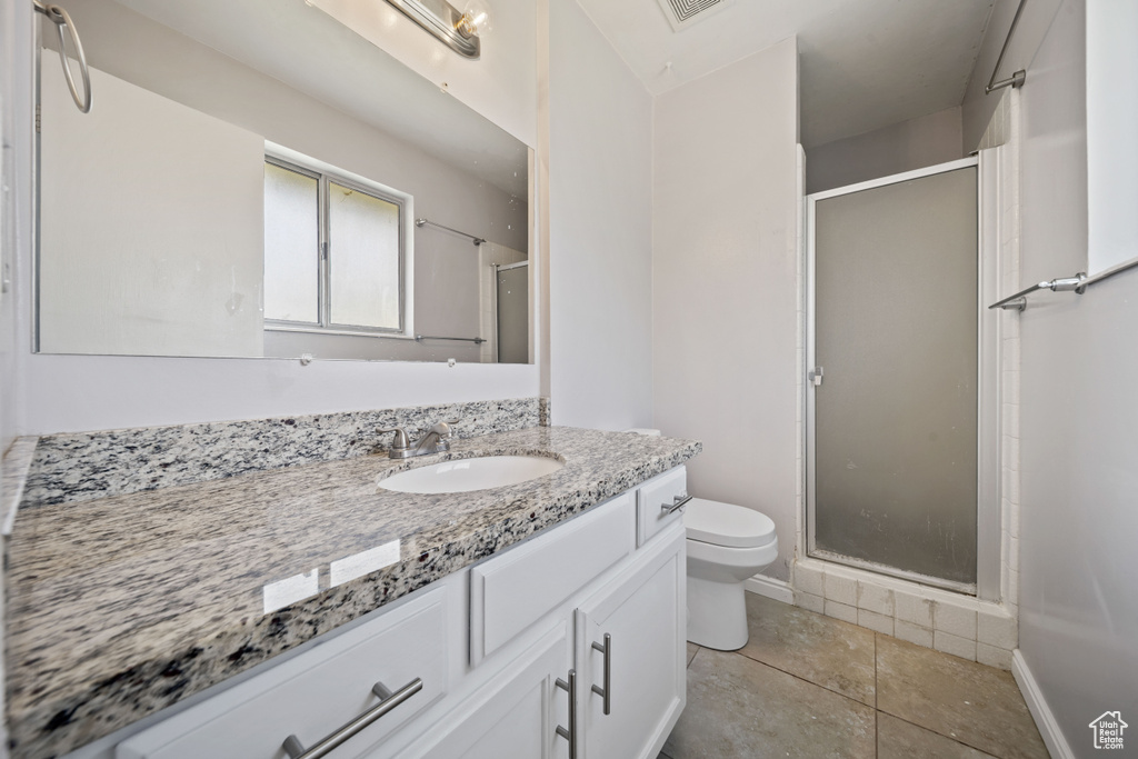 Full bath with a shower stall, toilet, vanity, and tile patterned floors