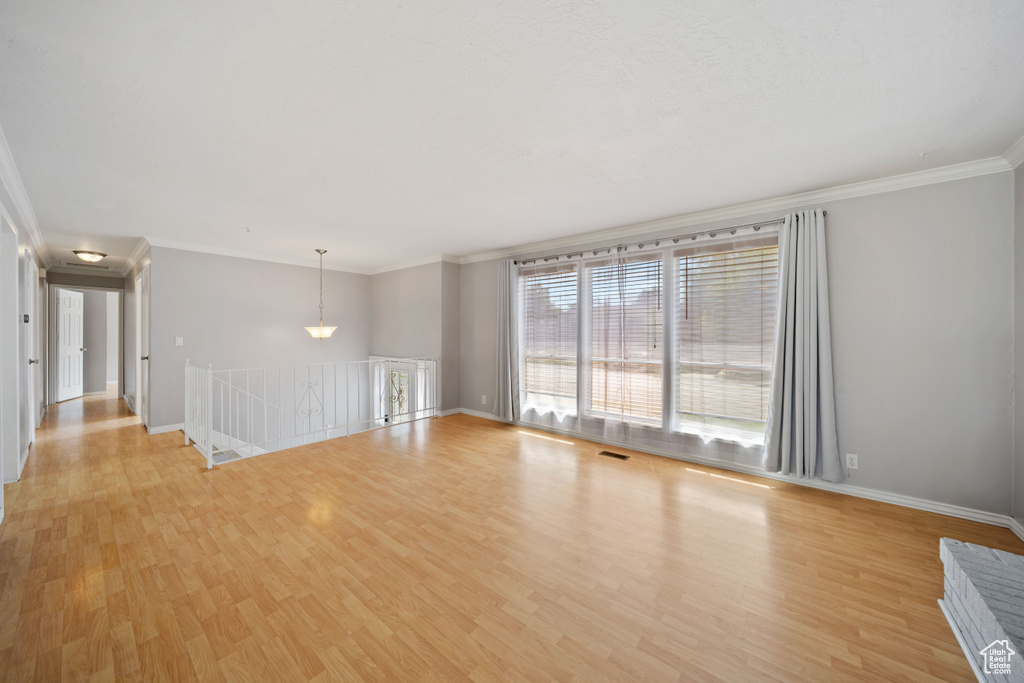 Unfurnished room with crown molding, light wood-style floors, and baseboards