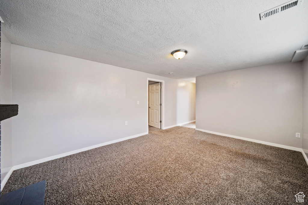 Carpeted spare room featuring baseboards and a textured ceiling