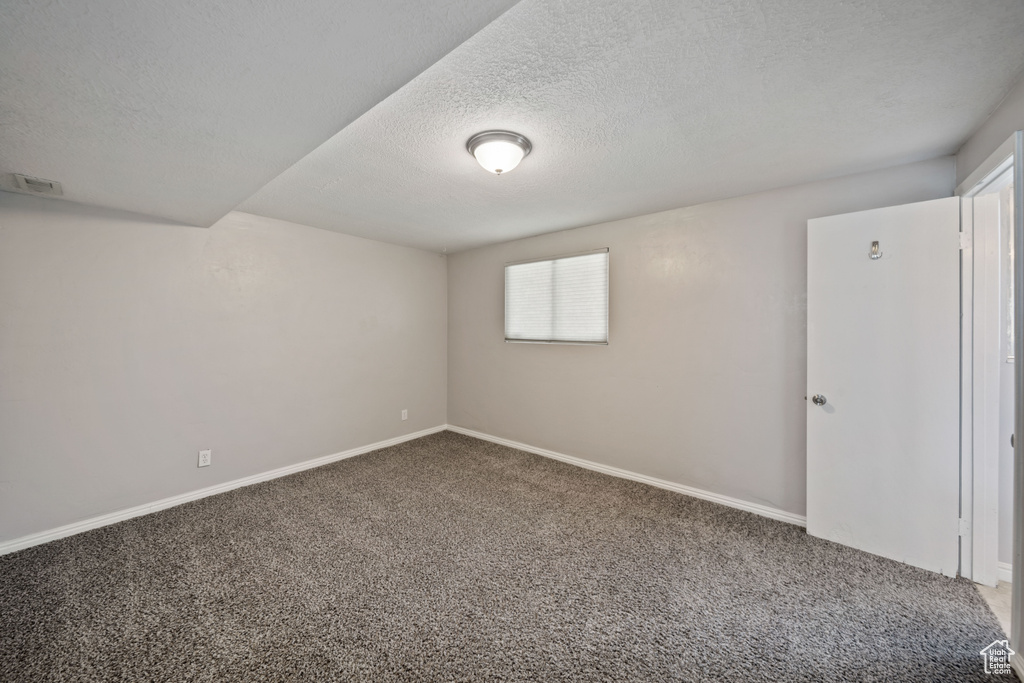 Spare room featuring carpet, a textured ceiling, and baseboards