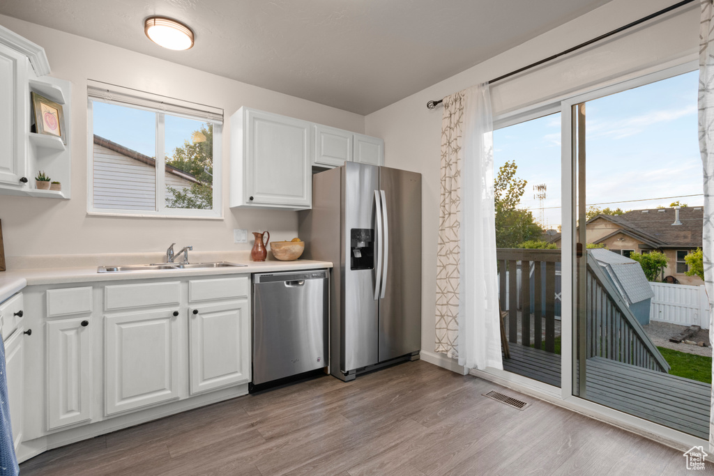 Kitchen featuring appliances with stainless steel finishes, a sink, light wood-style floors, and healthy amount of natural light