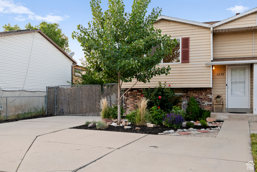 View of side of home with brick siding and a gate