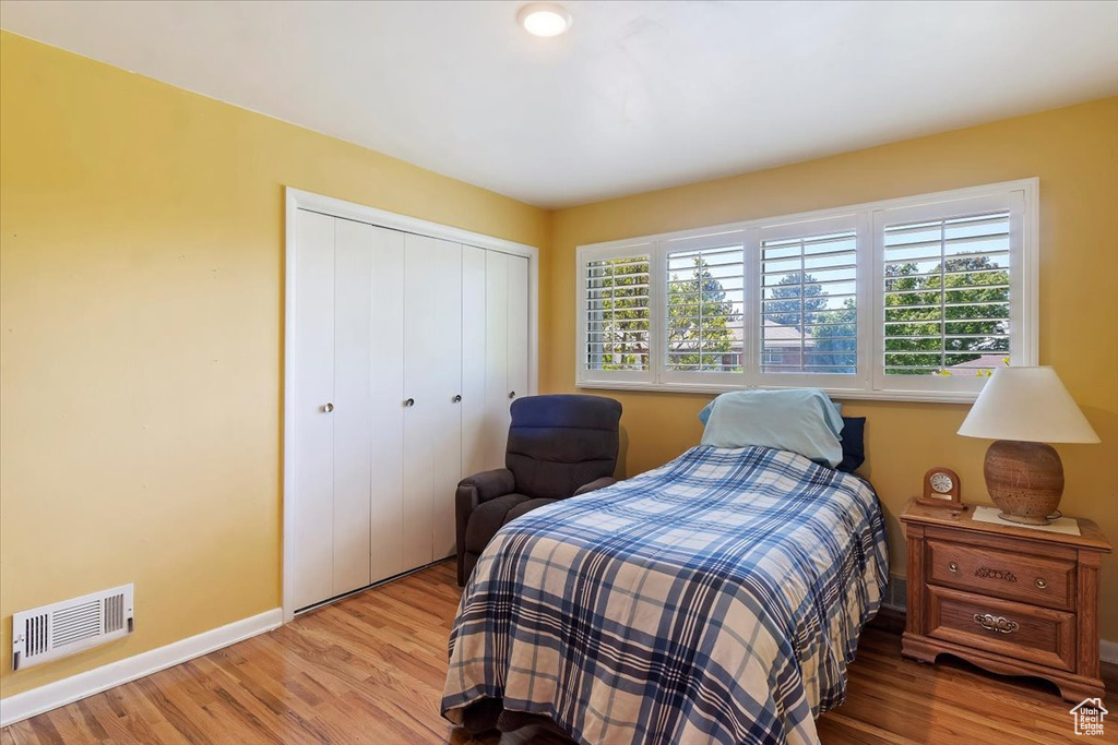 Bedroom with a closet, light wood-type flooring, and baseboards