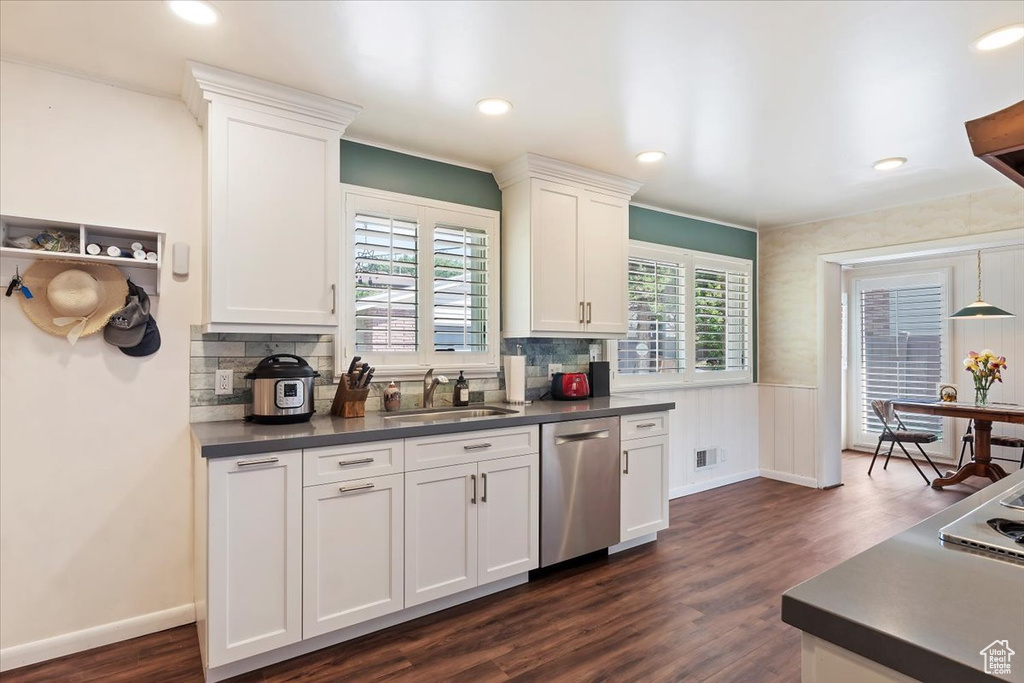 Kitchen featuring dishwasher, a sink, dark countertops, dark wood-style floors, and white cabinets