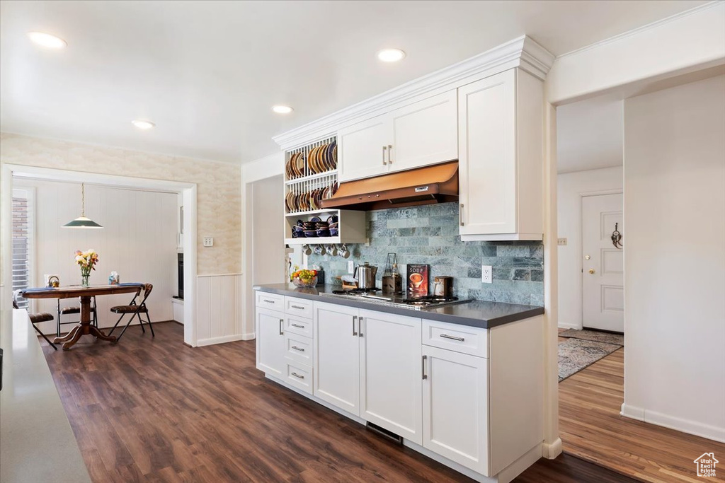 Kitchen featuring under cabinet range hood, stainless steel gas cooktop, dark countertops, dark wood-style flooring, and recessed lighting