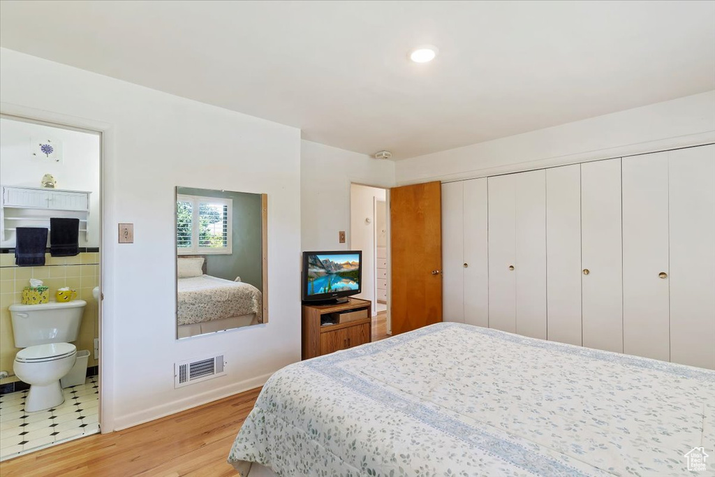 Bedroom featuring light wood-style flooring, ensuite bath, baseboards, and a closet