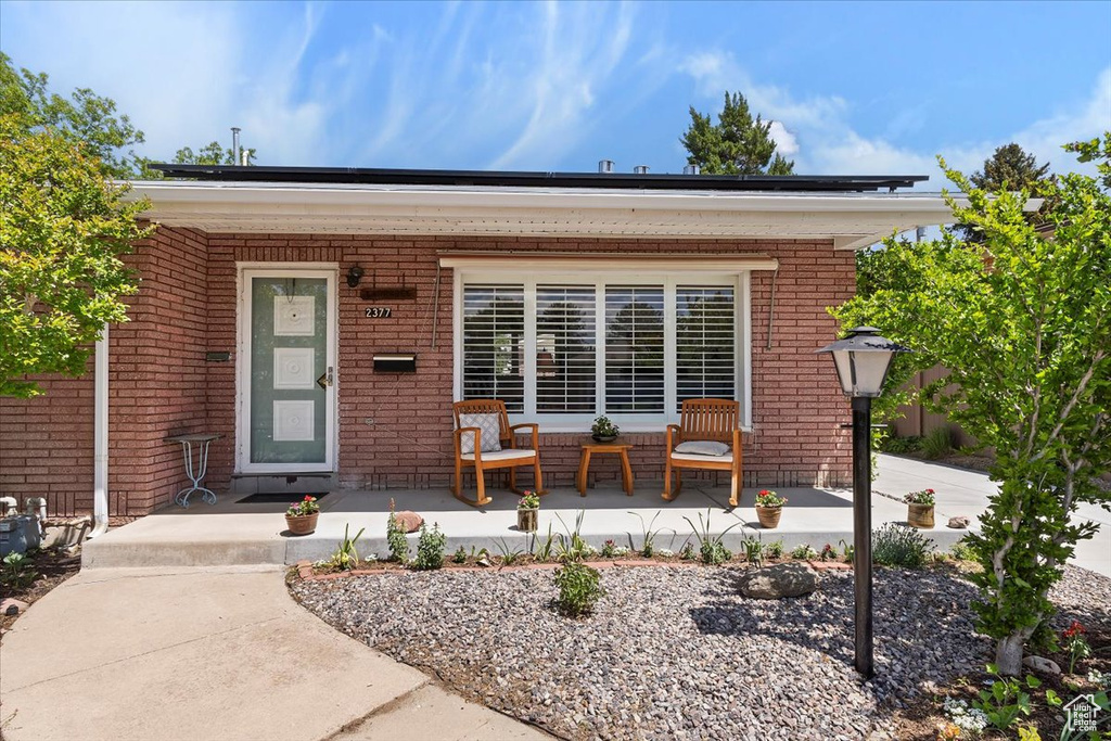 Entrance to property featuring a porch and brick siding