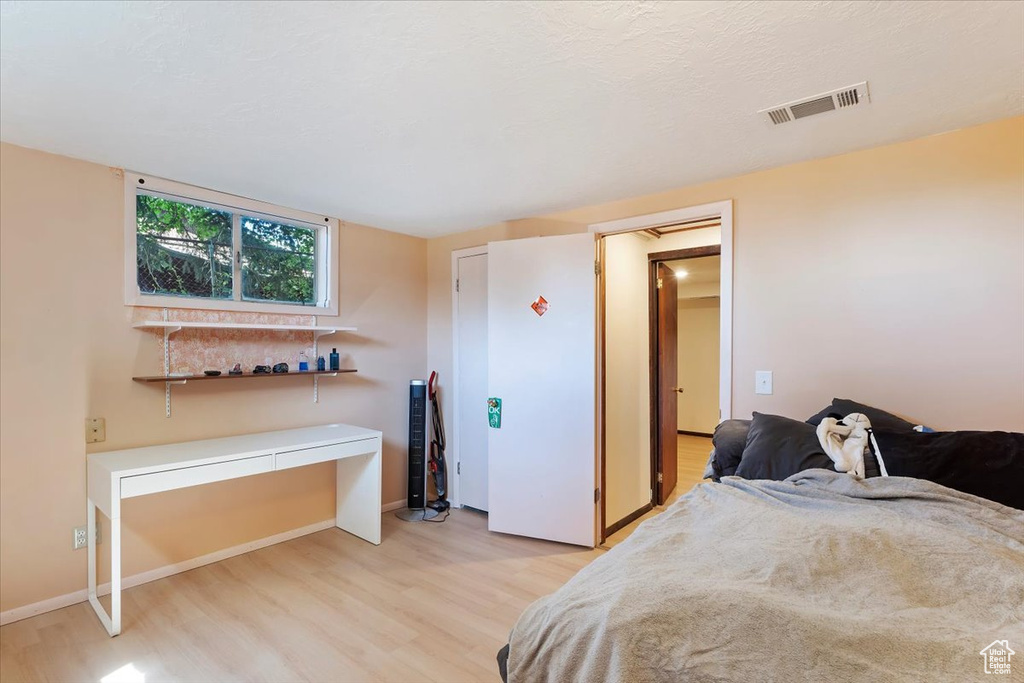 Bedroom with light wood-style flooring, baseboards, and an office area