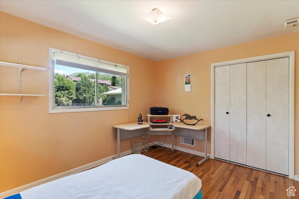 Bedroom with wood finished floors, a closet, and baseboards