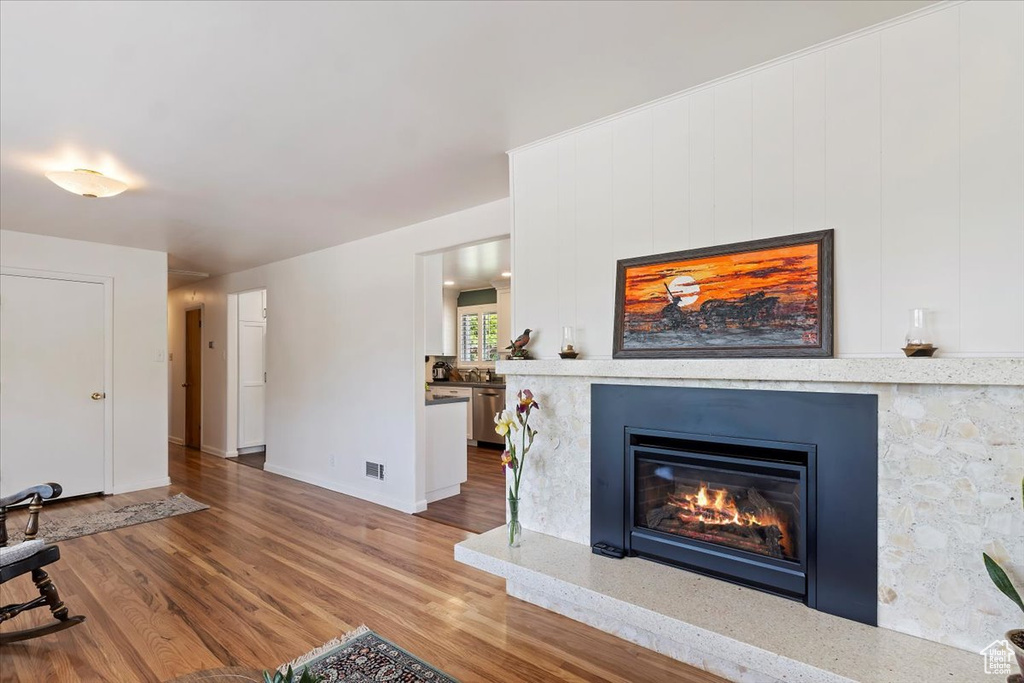 Living room with wood finished floors, a glass covered fireplace, and baseboards