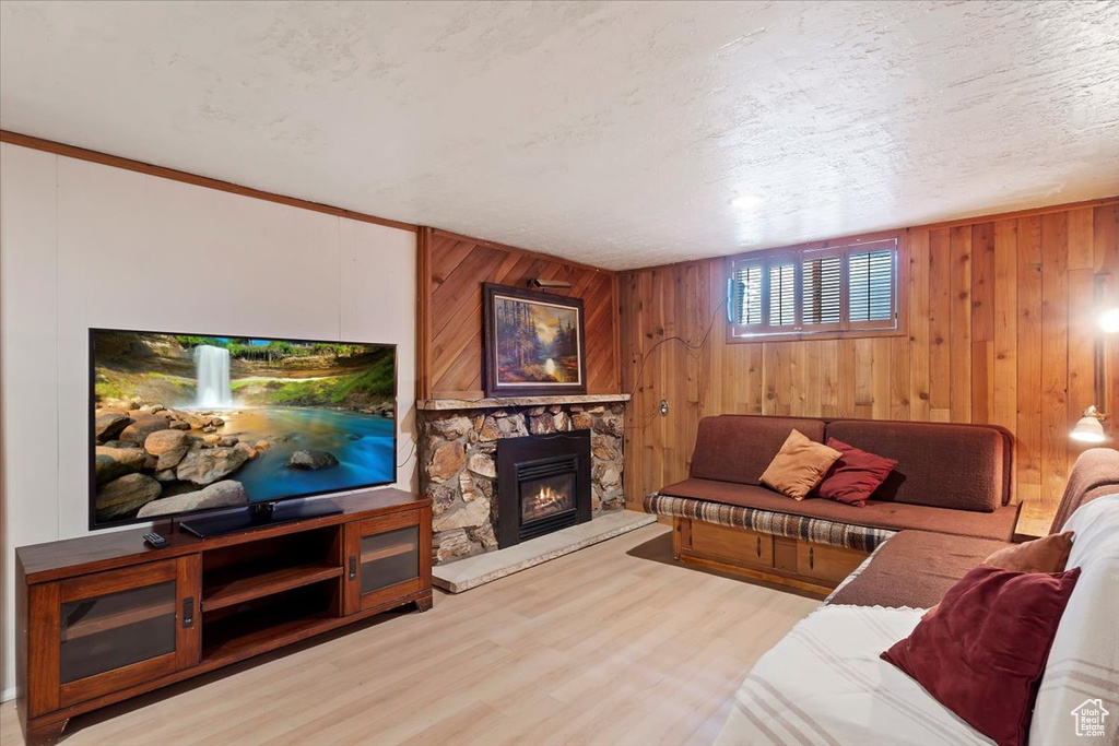 Living area featuring wood finished floors, a stone fireplace, and wooden walls