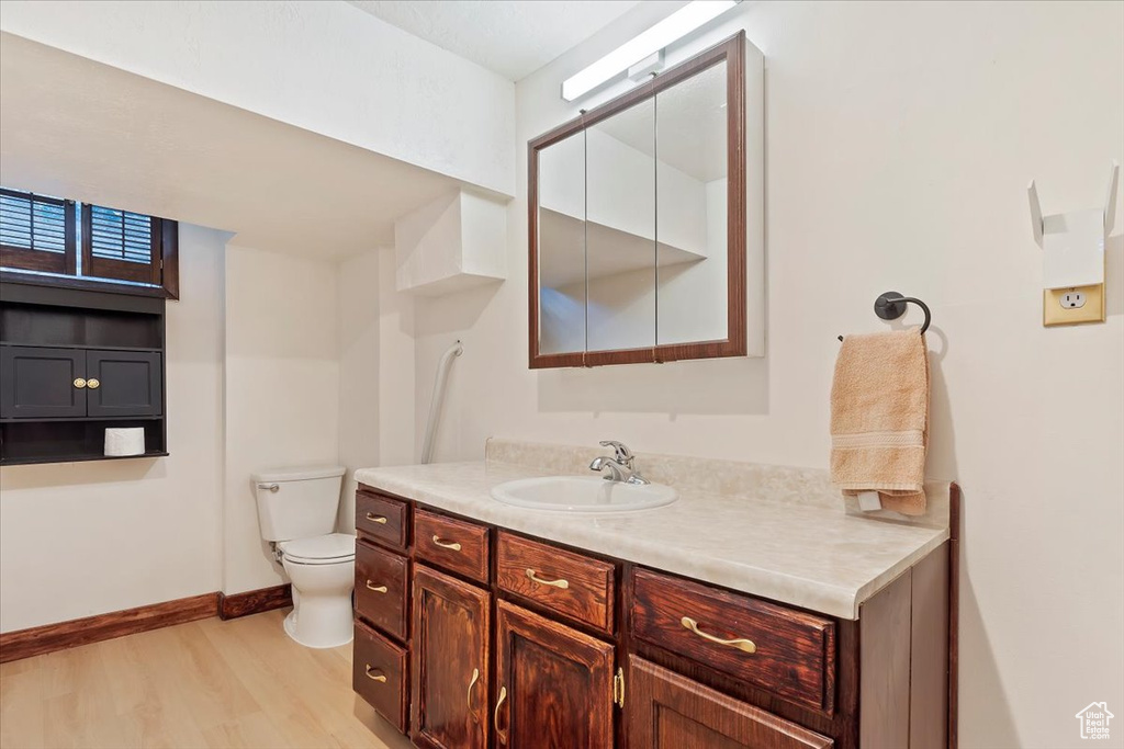 Bathroom featuring wood finished floors, toilet, vanity, and baseboards