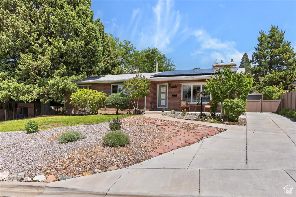 Single story home featuring solar panels and brick siding