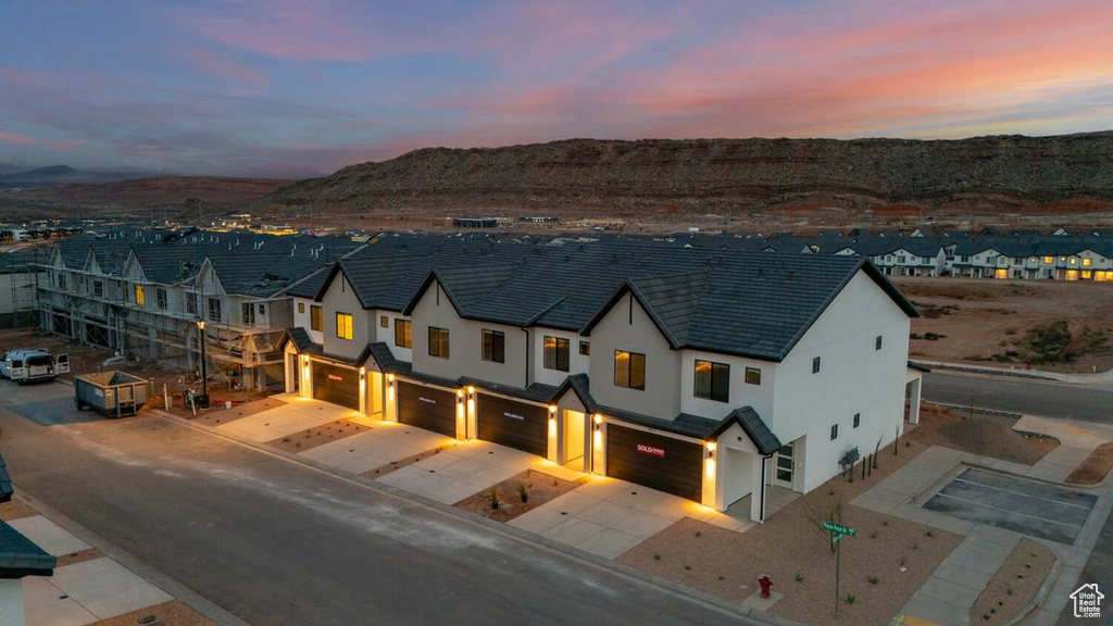 View of front of house with an attached garage, stucco siding, concrete driveway, and a mountain view