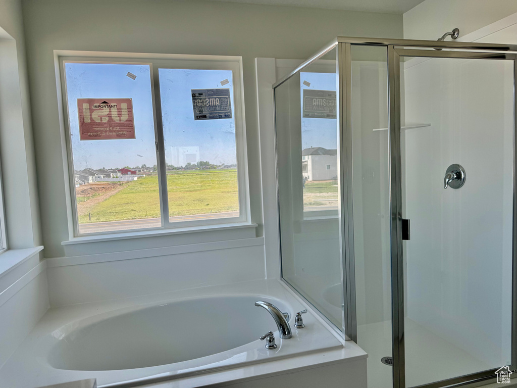 Full bath with healthy amount of natural light, a shower stall, and a bath