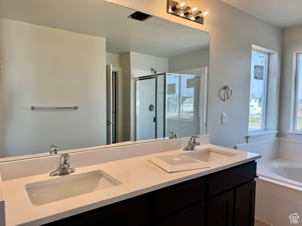 Bathroom with a stall shower, double vanity, and a garden tub