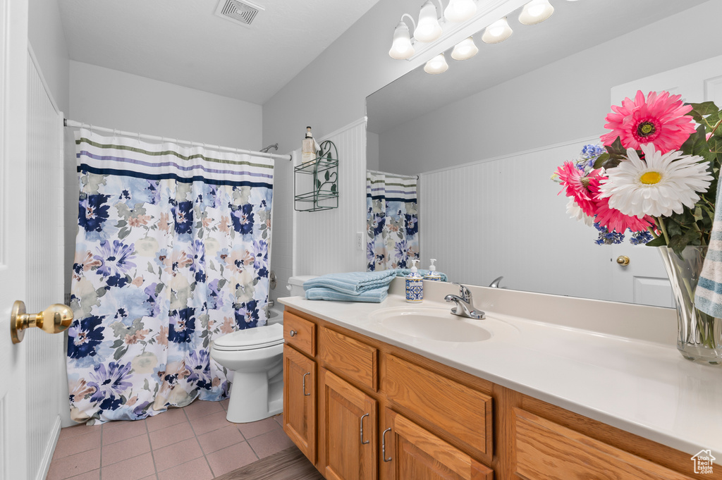 Bathroom featuring tile patterned floors, toilet, vanity, and curtained shower