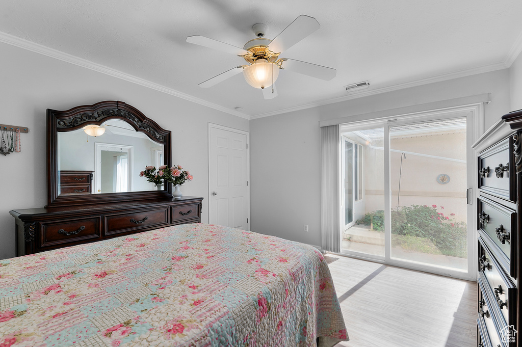 Bedroom featuring access to exterior, wood finished floors, crown molding, and a ceiling fan