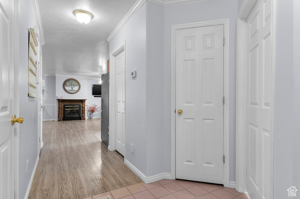 Hall with baseboards, light wood-type flooring, and a textured ceiling