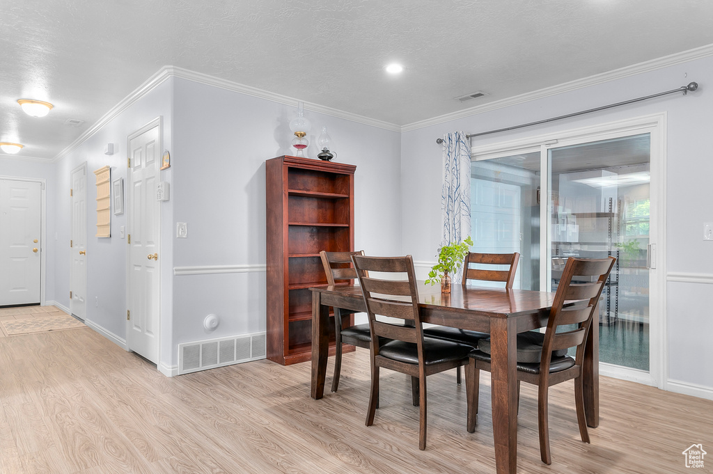 Dining room featuring light wood-type flooring, baseboards, and crown molding