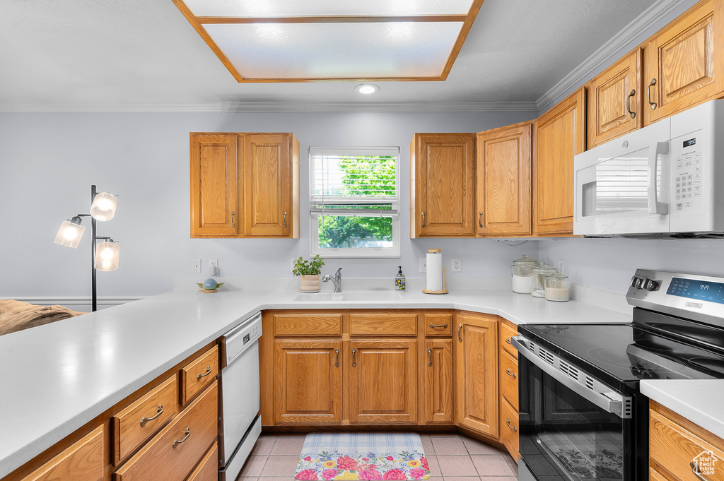 Kitchen featuring white appliances, a sink, light countertops, light tile patterned floors, and crown molding