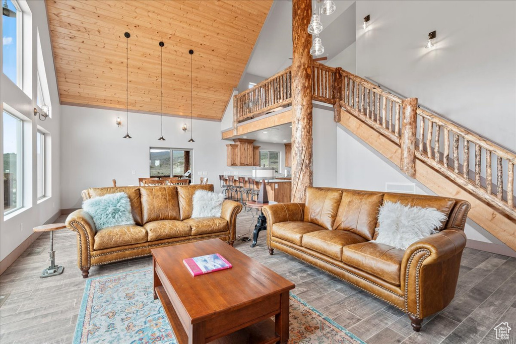 Living area with high vaulted ceiling, stairs, wood finished floors, baseboards, and wooden ceiling