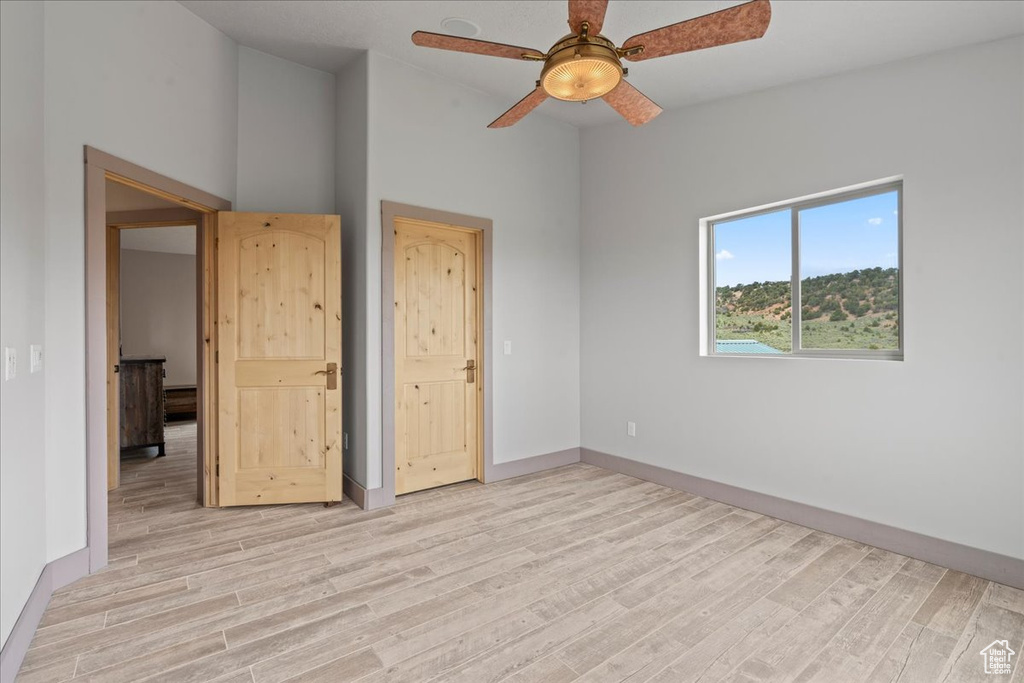 Spare room featuring light wood finished floors, ceiling fan, and baseboards