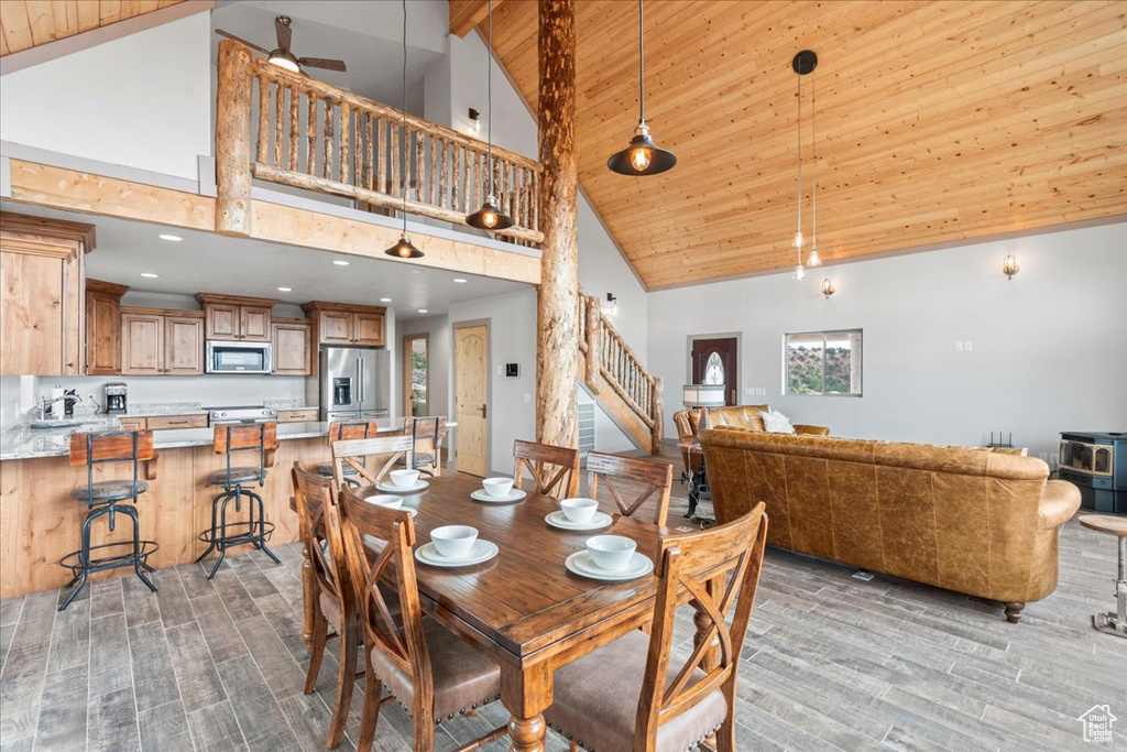 Dining room with high vaulted ceiling, light wood-type flooring, stairs, wooden ceiling with exposed beams, and recessed lighting