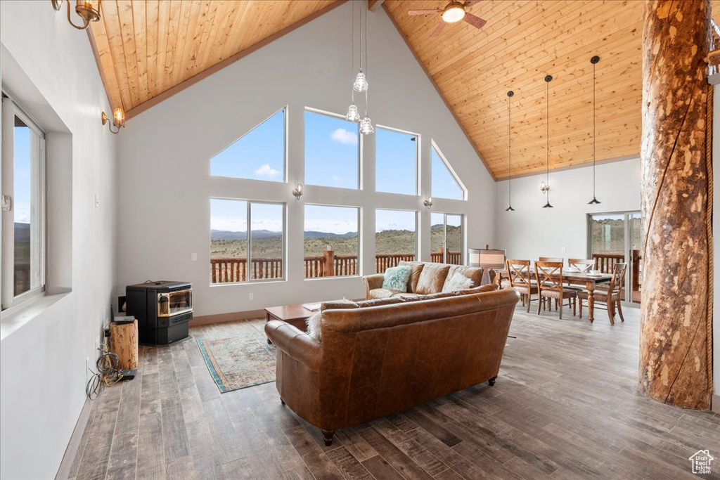 Living area with a wood stove, high vaulted ceiling, wood-type flooring, wood ceiling, and healthy amount of natural light