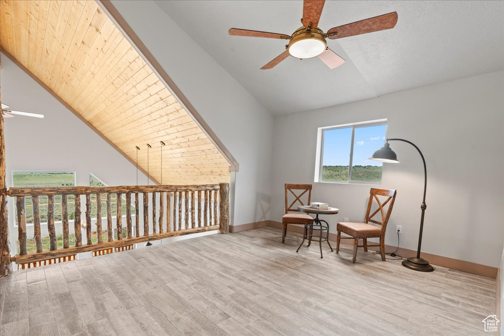 Sitting room with ceiling fan, high vaulted ceiling, wood finished floors, and baseboards